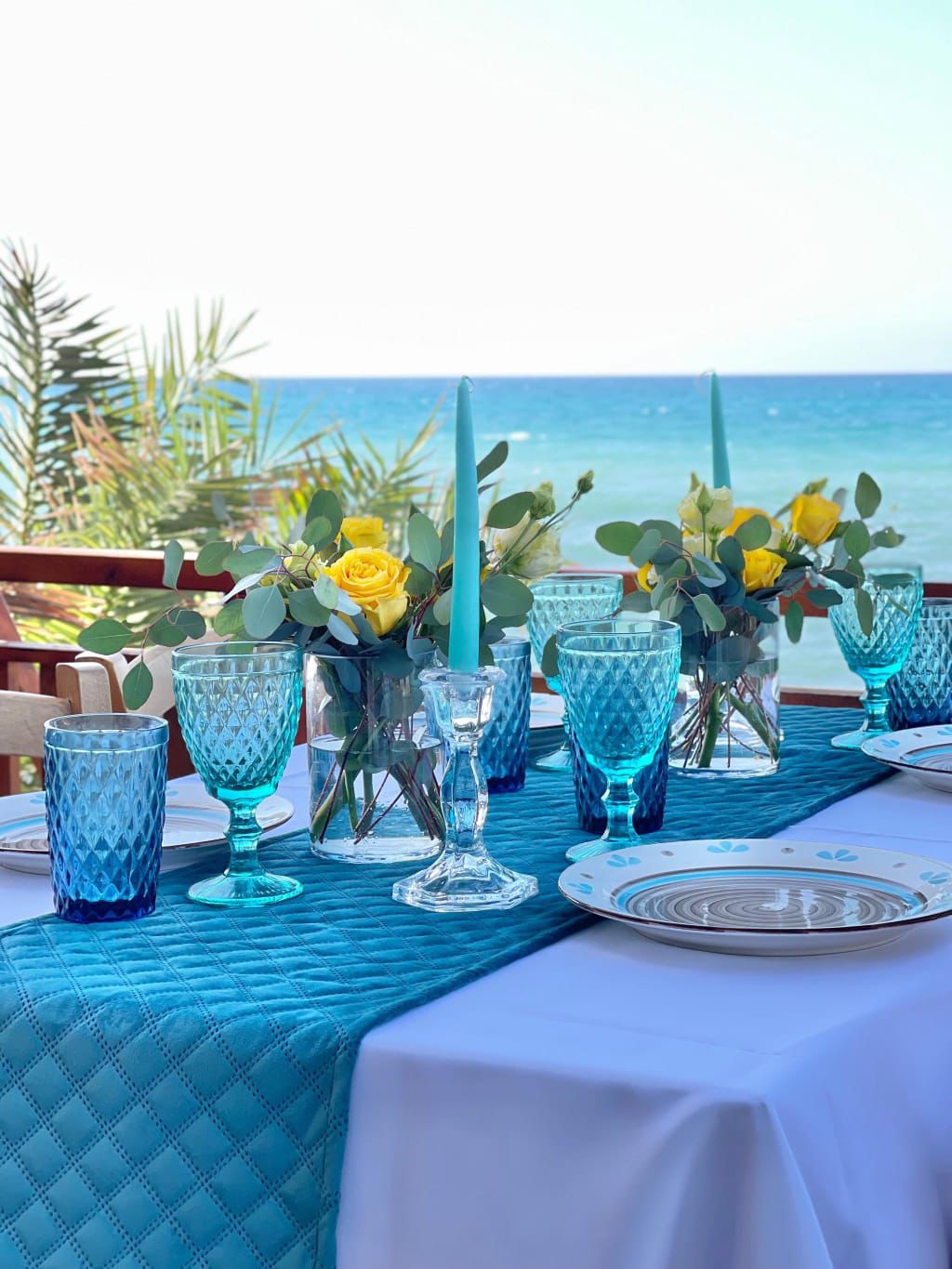 Turquoise candles, flowers and blue glasses on the terrace