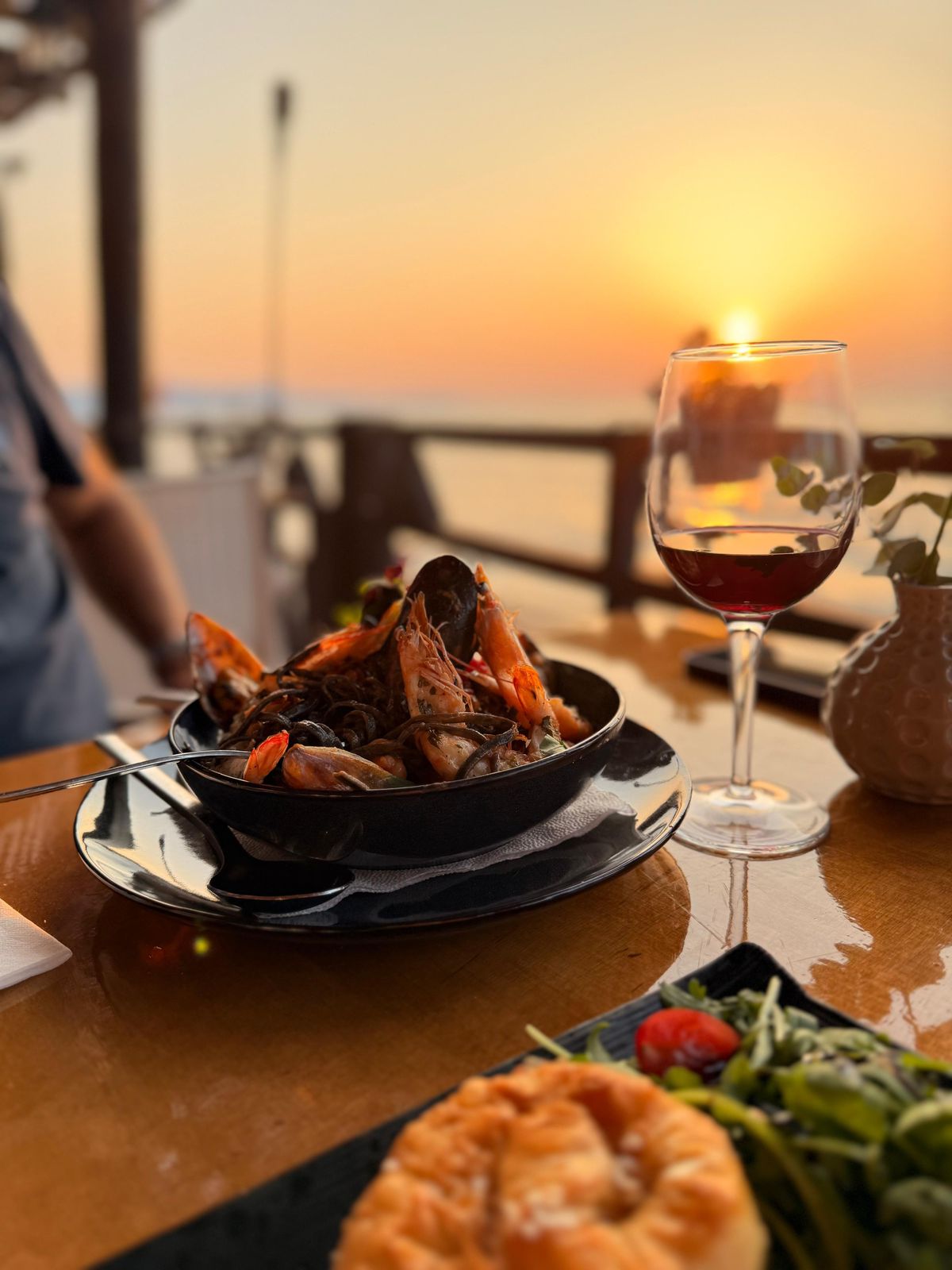 Seafood pasta and wine with a sunset sea view