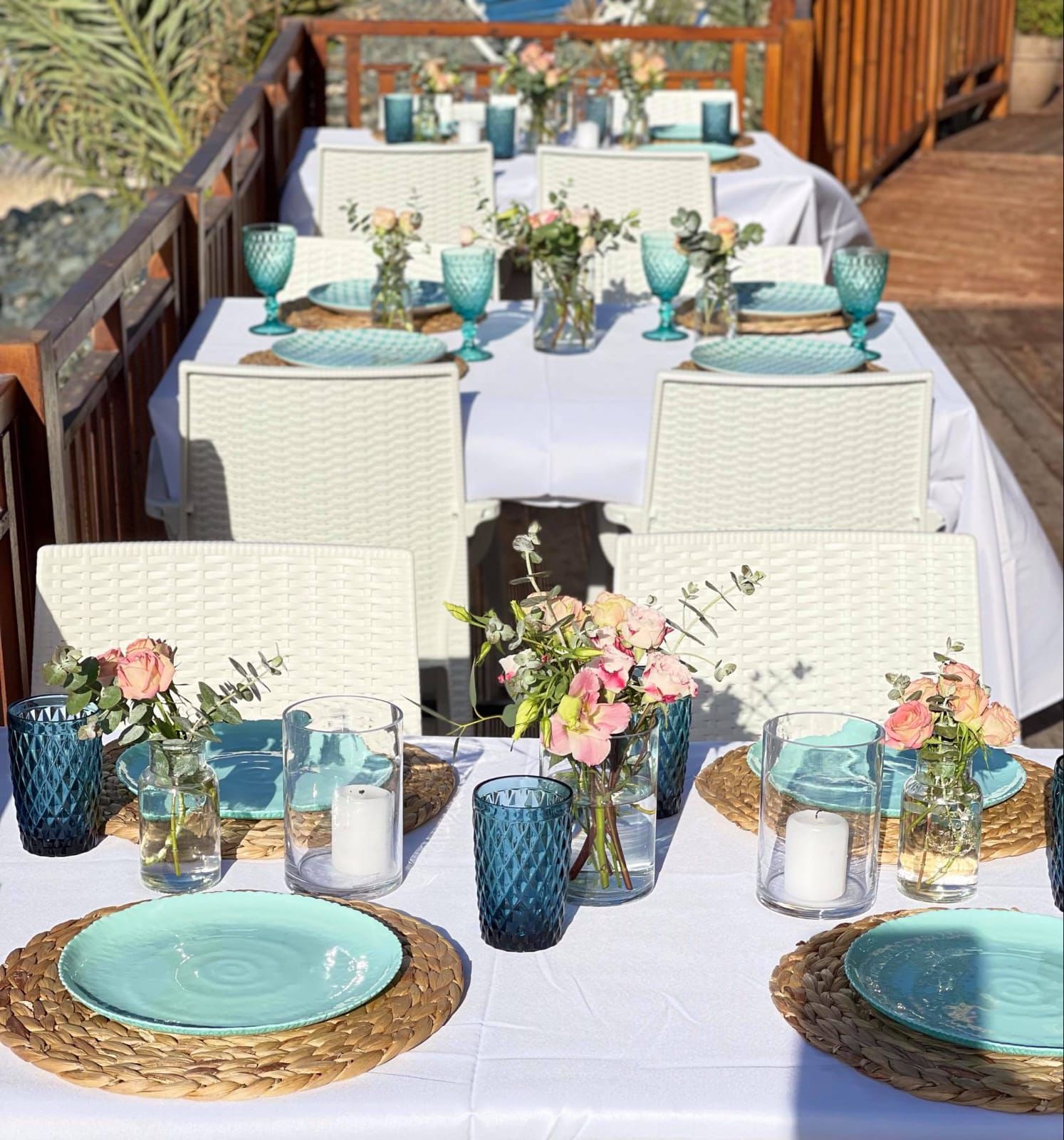 Terrace tables set with turquoise plates and flowers